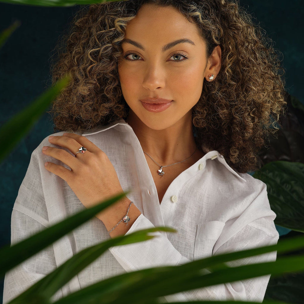 A woman with curly hair wearing a Clogau Pob Lwc Ring 3SLCL0609 and earrings.