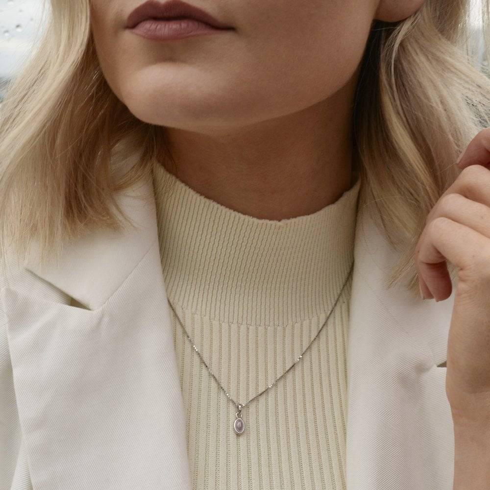 A woman wearing a white jacket and a Birthstone Necklace October – Rose Quartz.