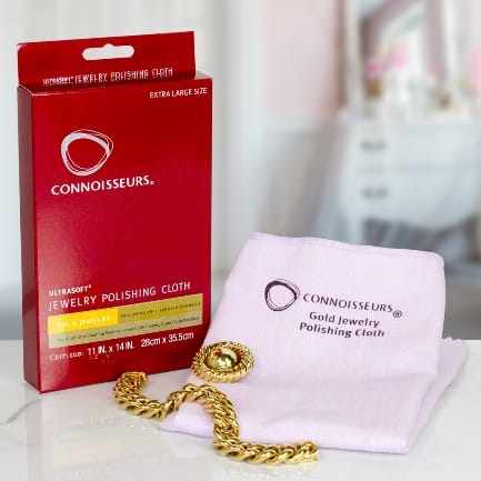 A pink towel with a CONNOISSEURS GOLD JEWELLERY POLISHING CLOTH next to it.