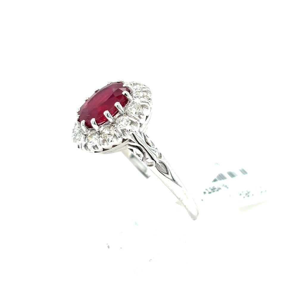The Ruby & Diamond Cluster Halo Set Dress Ring in 9ct white gold showcases an oval ruby center, encircled by sparkling diamonds in a stunning halo setting.