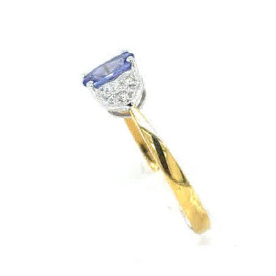 The Tanzanite and Diamond Cluster Dress Ring in 18ct yellow gold showcases a striking blue tanzanite center, accented by sparkling diamonds in a stylish cluster design.