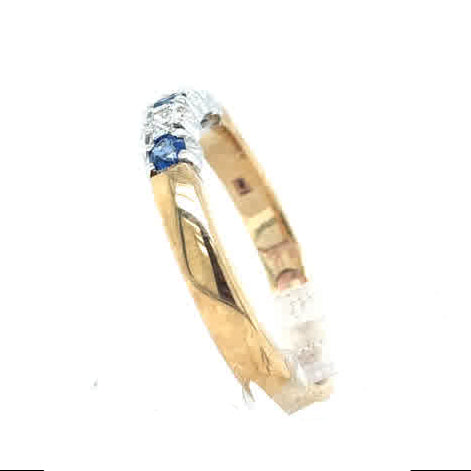 The Cym Welsh Gold Diamond and Sapphire Half Eternity Ring, featuring a small blue sapphire set into a gold band, is displayed against a white background.