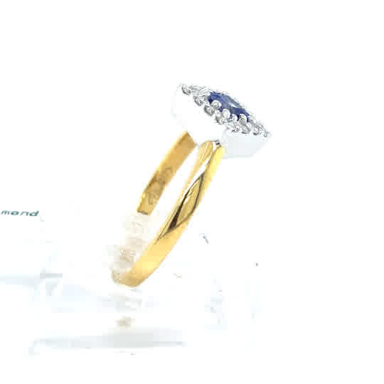 The Tanzanite and Diamond Cluster Dress Ring features 18ct yellow gold, showcasing a central blue tanzanite surrounded by sparkling diamonds in a rectangular silver setting, displayed on a transparent stand.