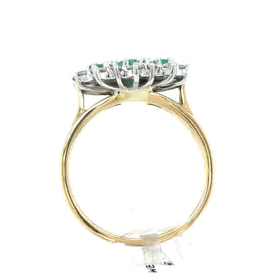 A 9ct yellow gold Emerald and Diamond Cluster Boat Dress Ring, viewed from the side, features a raised oval setting adorned with green gemstones and diamonds.