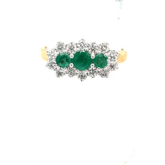 The Emerald and Diamond Cluster Boat Dress Ring in 9ct yellow gold features three oval green emeralds at the center, each surrounded by a floral halo of sparkling diamonds.