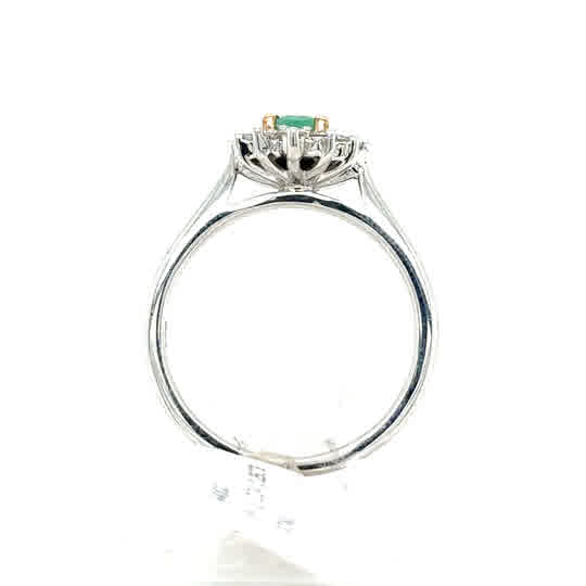 The Emerald and Diamond Cluster Ring in 9ct white and yellow gold features a green rectangular gemstone set at the center, showcased from the side against a white background.