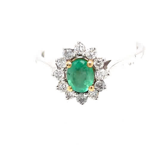 The Emerald and Diamond Cluster Ring features a vibrant oval-cut emerald, surrounded by sparkling round white diamonds, set in elegant 9ct white and yellow gold.