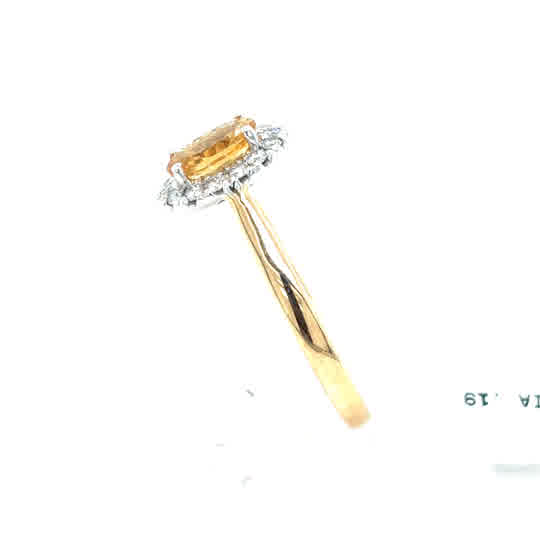 The Citrine & Diamond Halo Dress Ring in 9ct yellow gold displays an oval-cut citrine with a diamond halo, shown from the side against a white background.