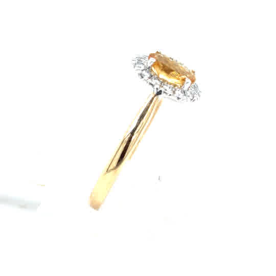 The Citrine & Diamond Halo Dress Ring in 9ct yellow gold features an oval citrine center with a diamond halo, presented against a white background.