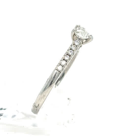 The Platinum Heart Diamond Engagement Ring features a heart-shaped center diamond with accent diamonds along the band, exuding timeless elegance.