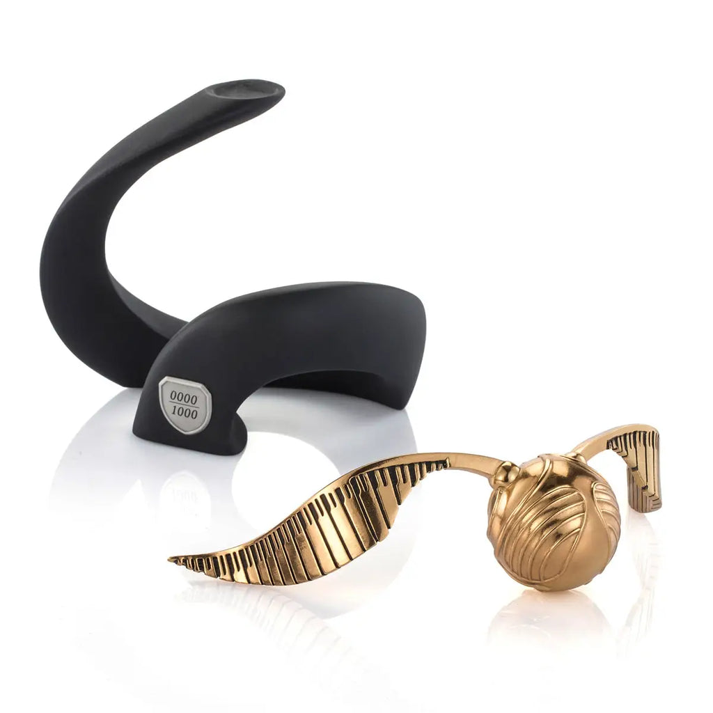 The Harry Potter Limited Edition Golden Snitch Replica is a gold winged ball with engraved details, displayed on a black curved stand and individually numbered "0000/1000.