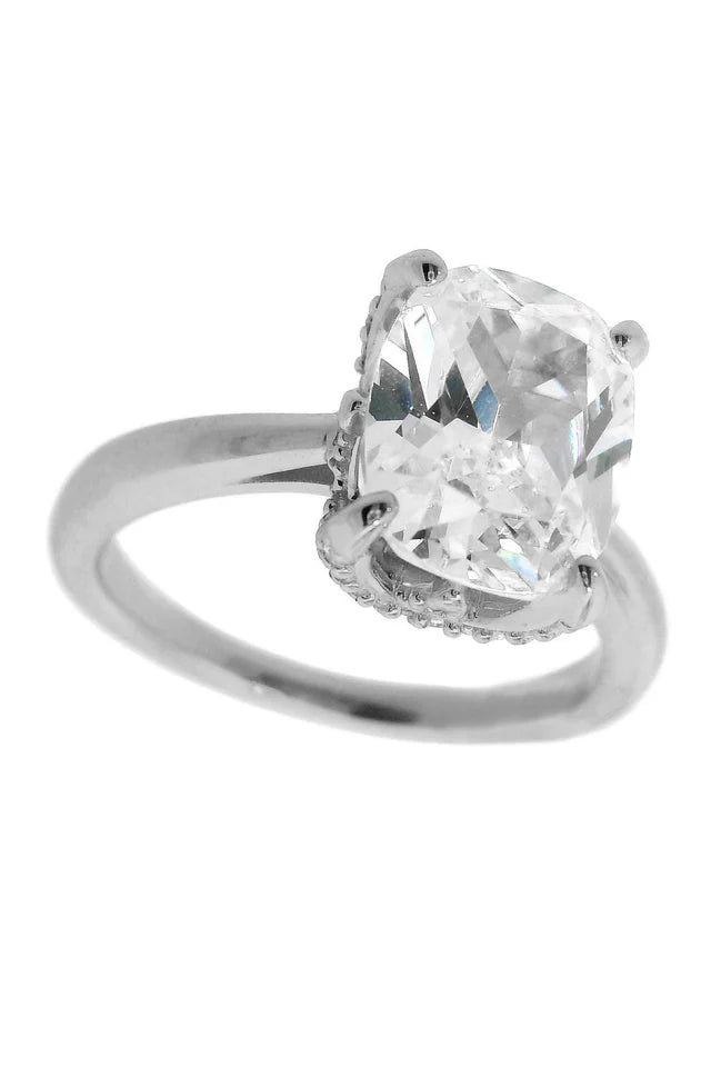 The Georgini Sydney Soirée Elaine Cushion Cut Ring Silver is crafted from rhodium-plated 925 sterling silver and showcases a large, clear cushion-cut gemstone in an elegant four-prong setting.