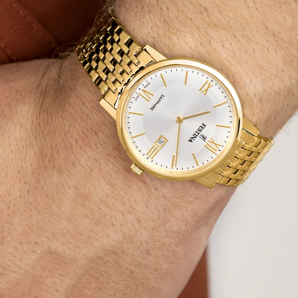 A Festina Men's Silver Dial Watch (F20020/1) with a gold tone strap, Swiss made, is worn on the left wrist. The silver dial enhances its sleek appearance, and "Festina" is displayed on the face.