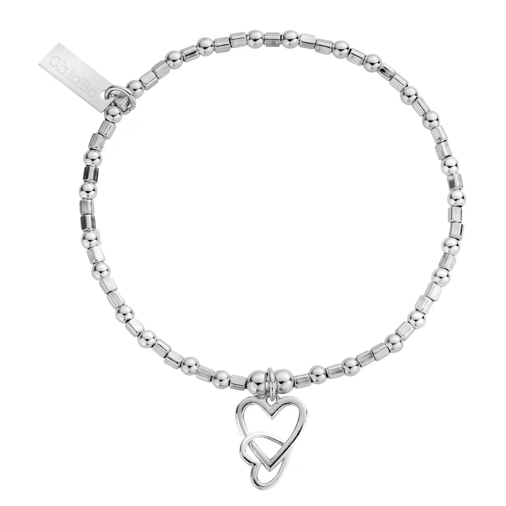 The ChloBo Mini Cube Interlocking Love Heart Bracelet features silver beads, double heart charms, and a rectangular engraved tag—an ideal gift for her.