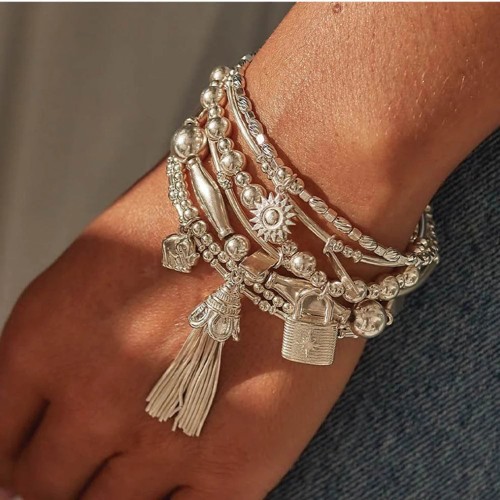 A hand wearing multiple silver beaded bracelets, including the ChloBo Cute Charm Elephant Bracelet and other pieces featuring charms like a padlock, tassel, sun, and symbolic jewelry elements.