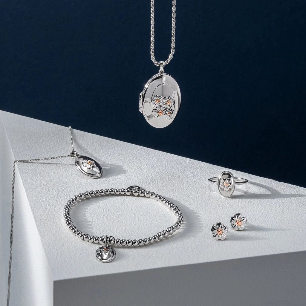 A collection of Clogau Forget Me Not Locket 3SFMN0618 jewelry on a white surface.