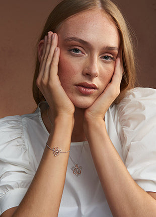 A woman wearing a NEW Clogau Fairies of the Mine Bracelet 3SETL0229 with her hands on her face.