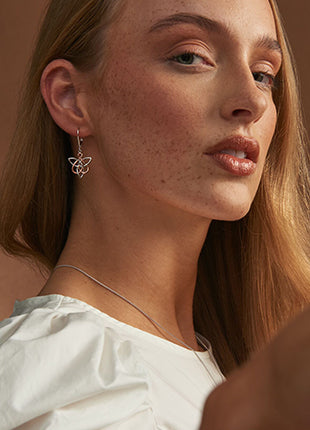 A woman wearing a white shirt and a pair of NEW Clogau Fairies of the Mine Drop Earrings 3SETL0231.