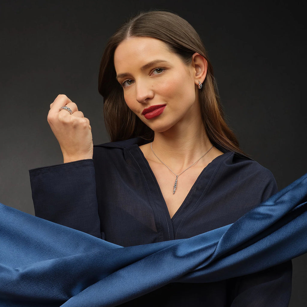 A woman in a blue shirt is posing for a photo wearing the Clogau Lover’s Twist Ring 3SLTW0615.