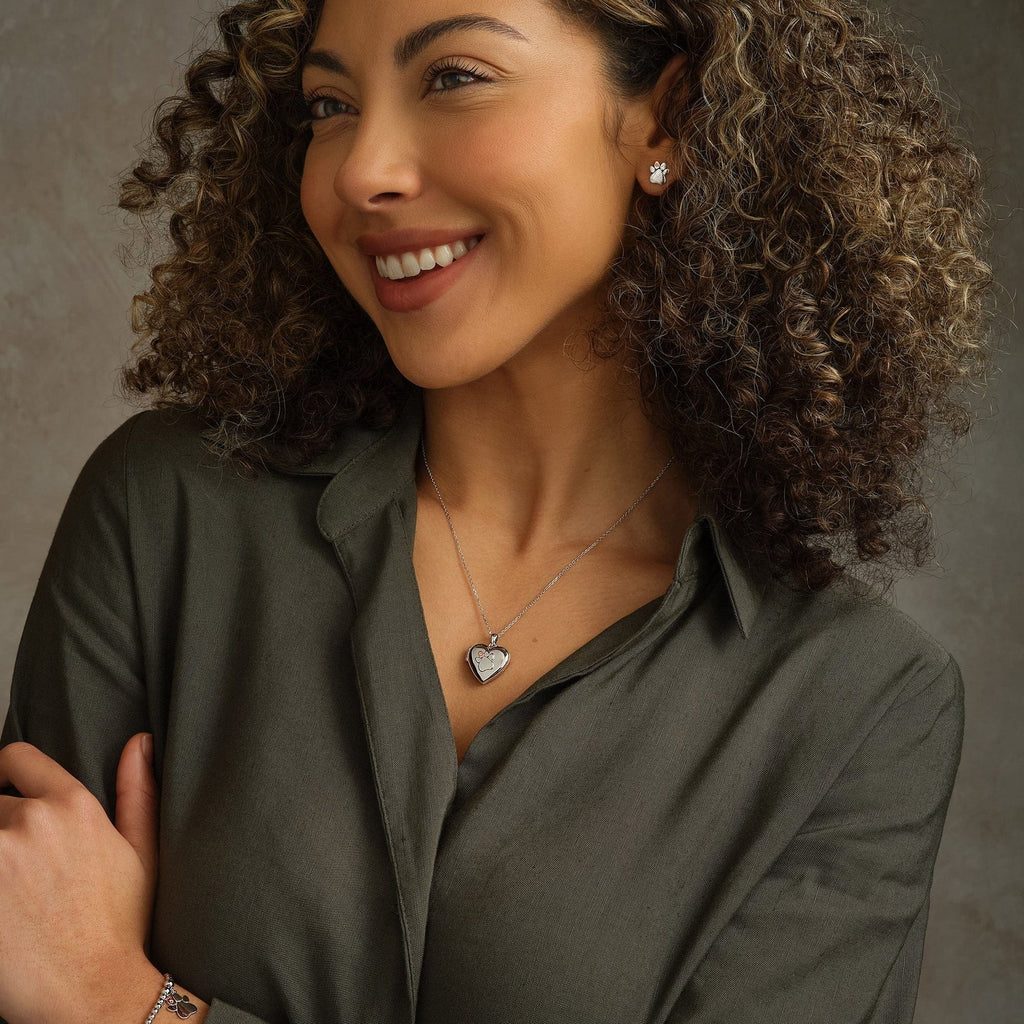 A woman with curly hair smiles while wearing a Clogau Paw Print Heart Locket 3SPWP0617 shirt.