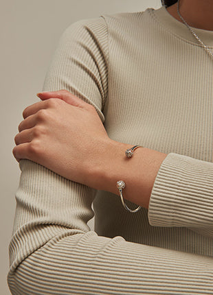 A woman wearing a tan sweater and the NEW Clogau Tudor Court Spherical Pearl Bangle 3STDC0333 bracelet.