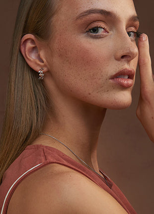 A woman is posing with the NEW Clogau Vine of Life White Topaz Half Hoop Earrings 3STOL0235 on her face.