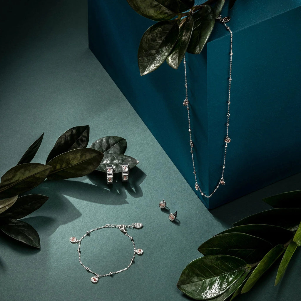 A silver necklace, earrings and the Clogau Tree of Life Insignia Bracelet 3STOL0602 on a blue background.