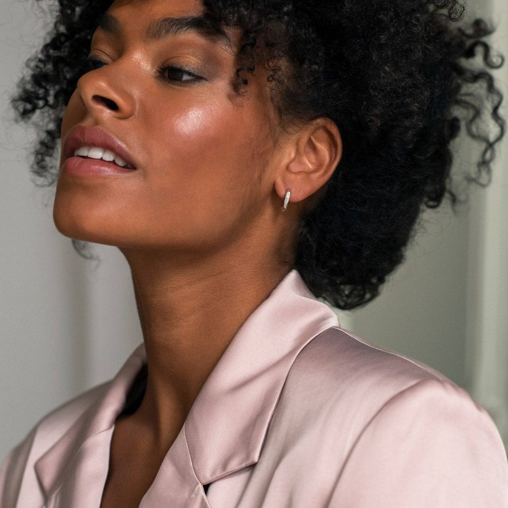 A black woman in a pink suit looking up at the camera wearing TI SENTO Milano Earrings.