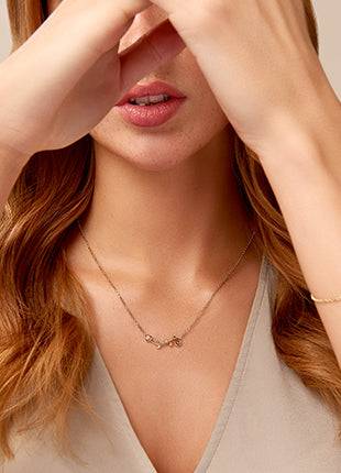 A woman wearing a Vines of Life Diamond Necklace with a heart on it.