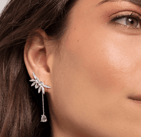 A woman wearing a pair of Leaves Silver Drop Earrings with diamonds.