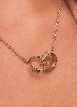 A woman wearing a Clogau Tree of Life Insignia Links Necklace TOLMNN with two rings on it.