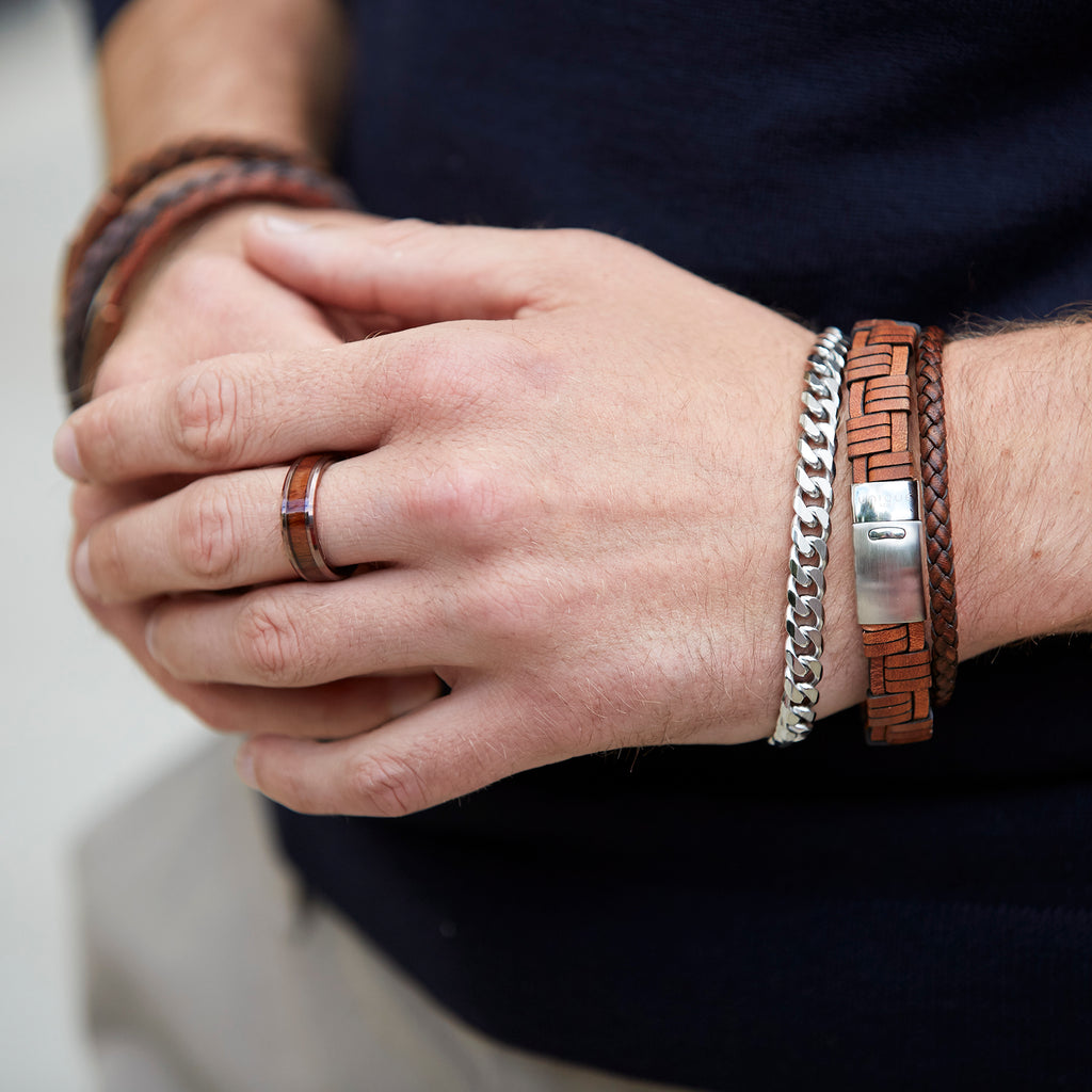 A man wearing a pair of MEN'S LEATHER BRACELET BLACK B425BL BY UNIQUE & CO bracelets.