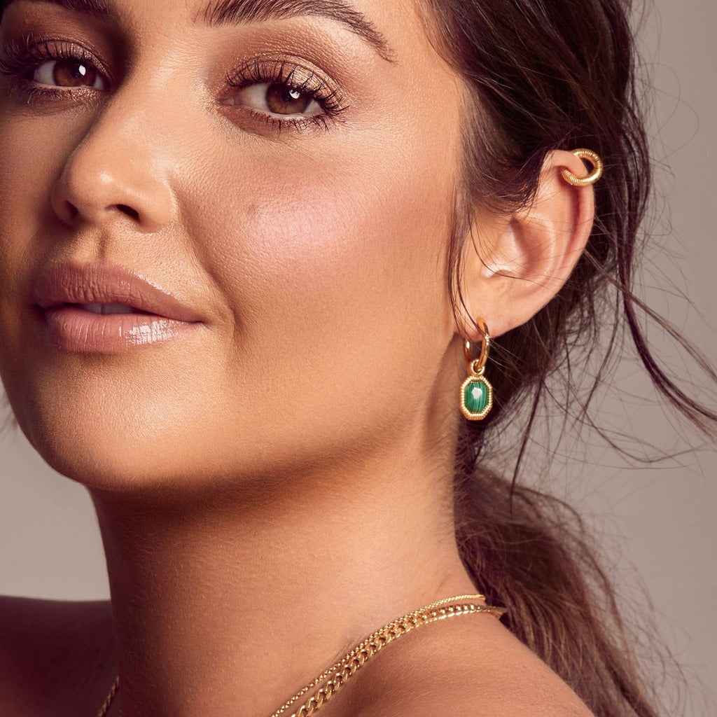 A woman wearing a Hot Diamonds X Jac Jossa Revive Malachite Earring with emerald stones.