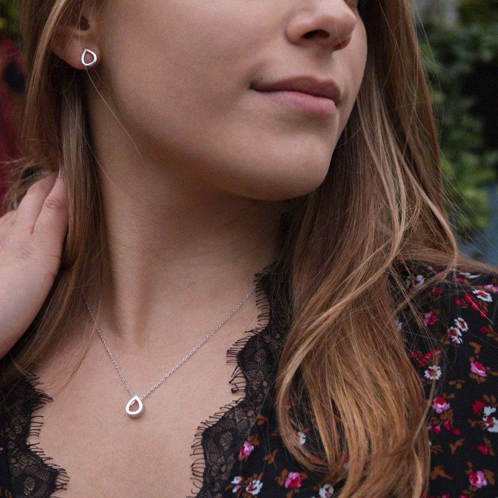 A young woman wearing a HOT DIAMONDS Amulets Teardrop Gift Set – SS135 necklace and earrings.