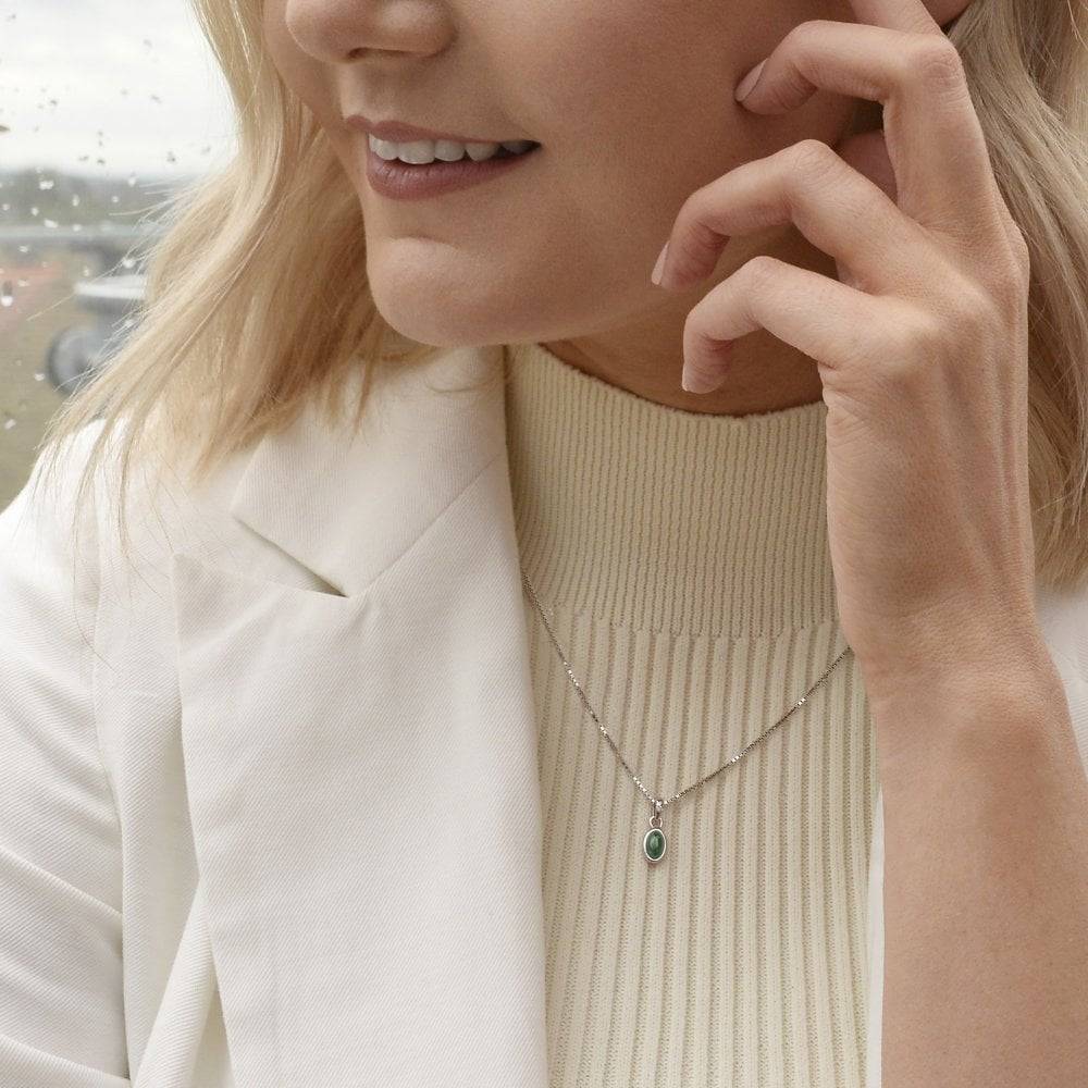 A woman wearing a white jacket and a Birthstone Necklace May – Green Agate.