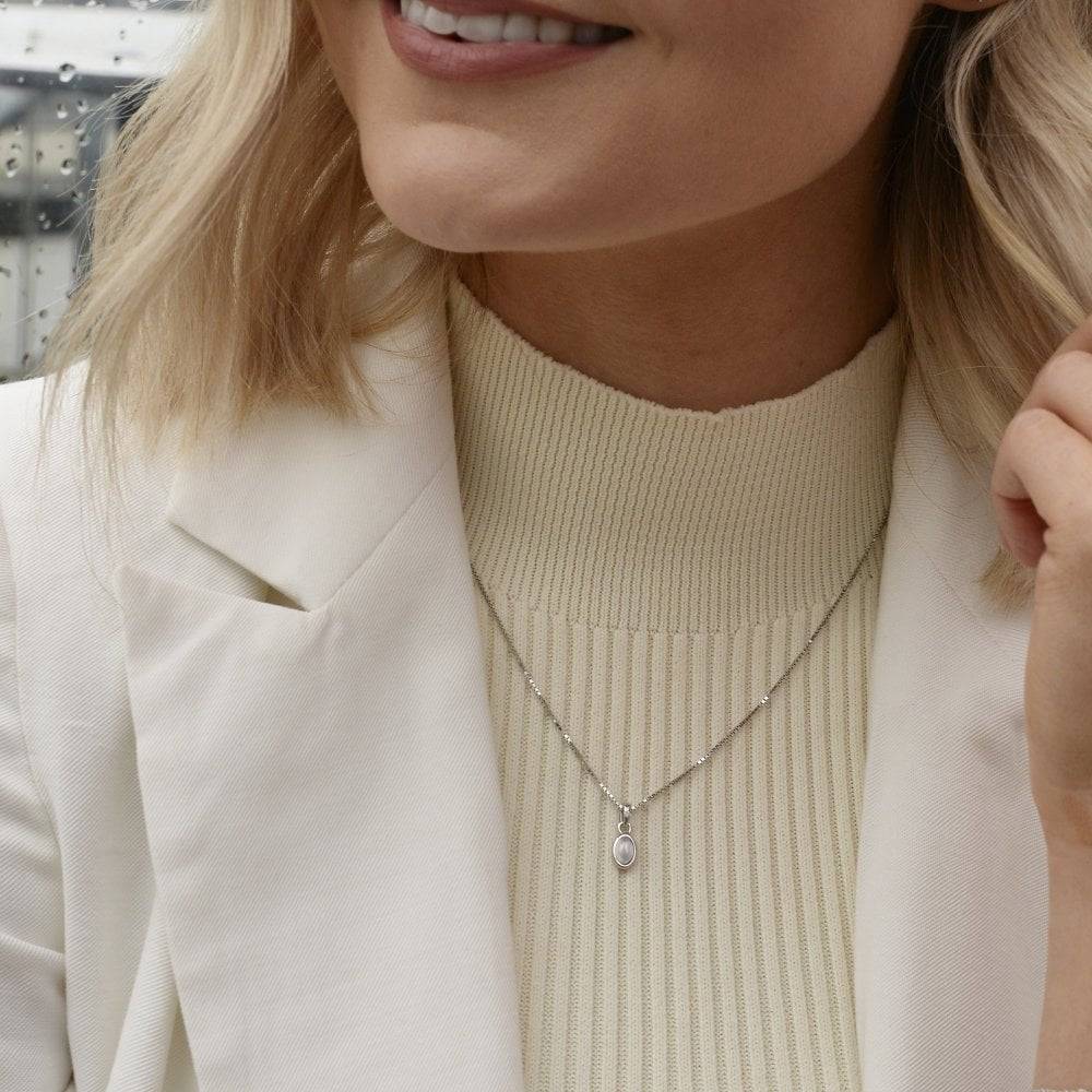 A woman wearing a white jacket and a Birthstone Necklace June- Moonstone.