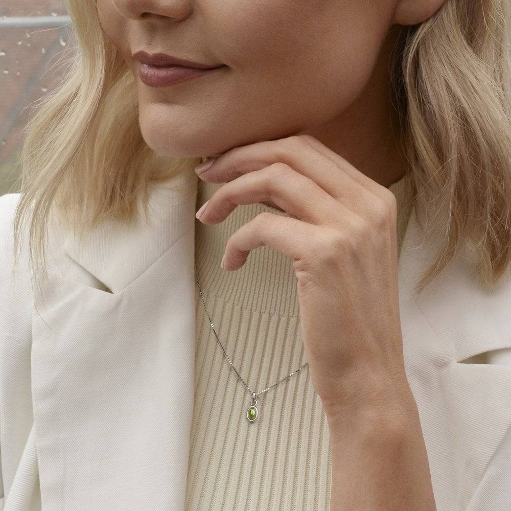 A woman wearing a white jacket with a Birthstone Necklace August- Peridot.