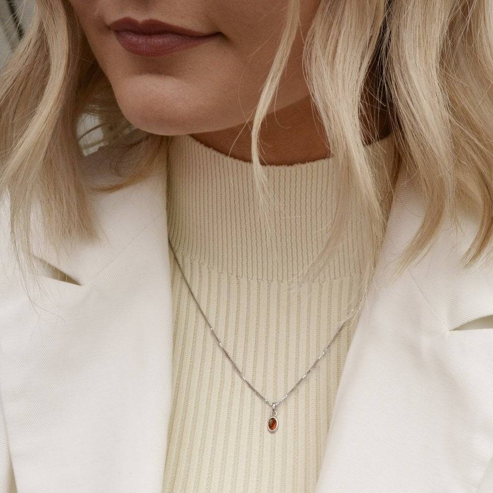 A woman wearing a white jacket and a Birthstone Necklace July – Red Carnelian.
