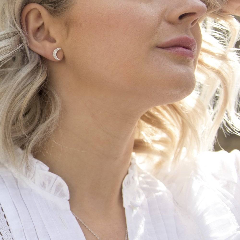 A woman wearing a white shirt and HOT DIAMONDS Striking Crescent Earrings. – DE553.