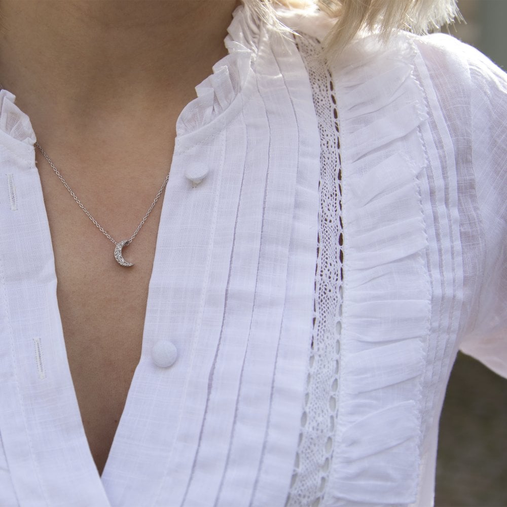 A woman wearing a white shirt and a HOT DIAMONDS Striking Crescent Pendant. – DP698 necklace.