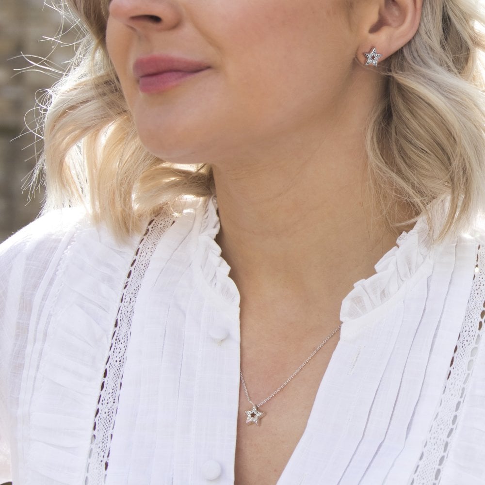 A woman wearing a white shirt and HOT DIAMONDS Striking Star Pendant. – DP697 earrings.