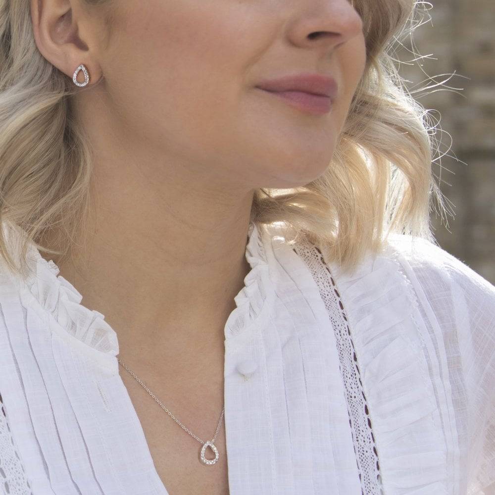A woman in a white shirt wearing HOT DIAMONDS Striking Teardrop Earrings. – DE555 necklace and earrings.