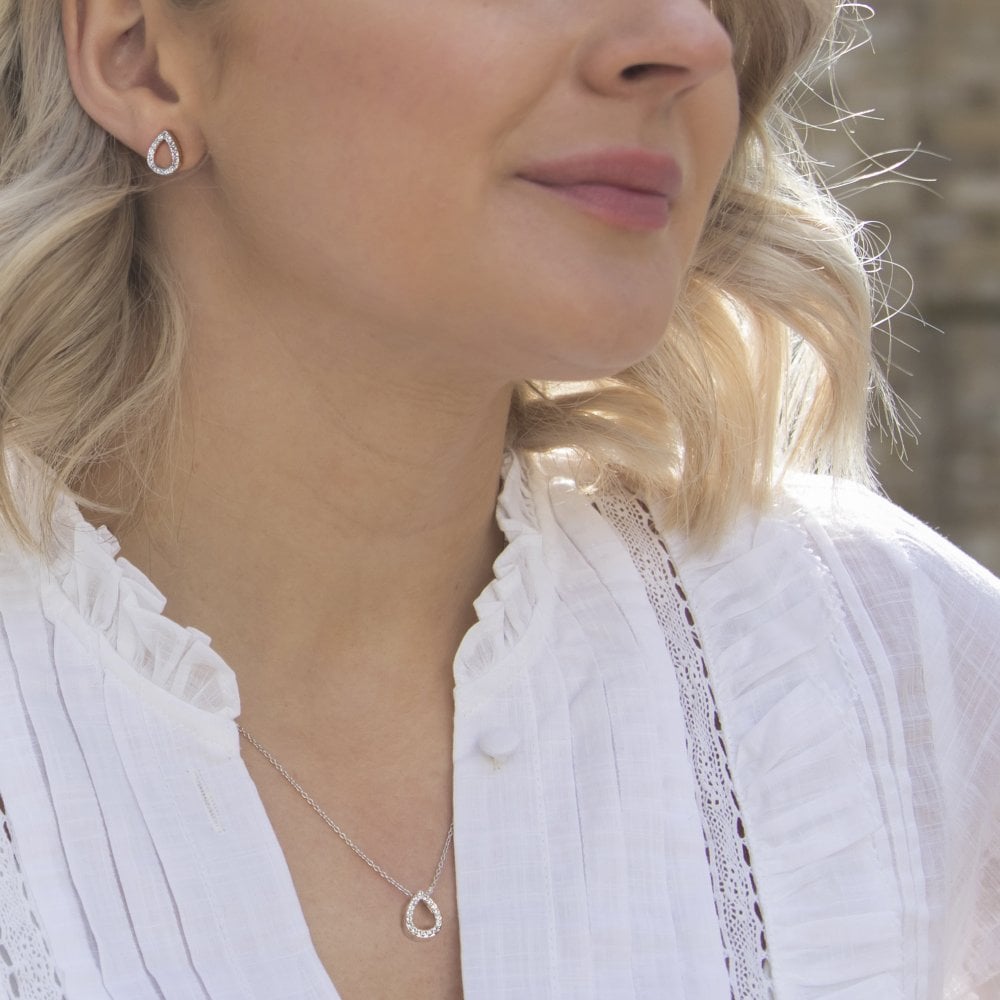 A woman in a white shirt wearing the HOT DIAMONDS Striking Teardrop Pendant. – DP695 necklace and earrings.