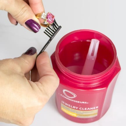 A person using CONNOISSEURS PRECIOUS JEWELLERY CLEANER to clean a jar of polish.