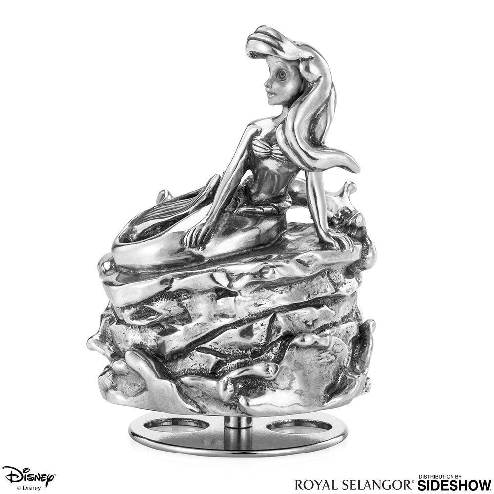 An Ariel Music Carousel 016305R figurine sitting on top of a piece of metal.